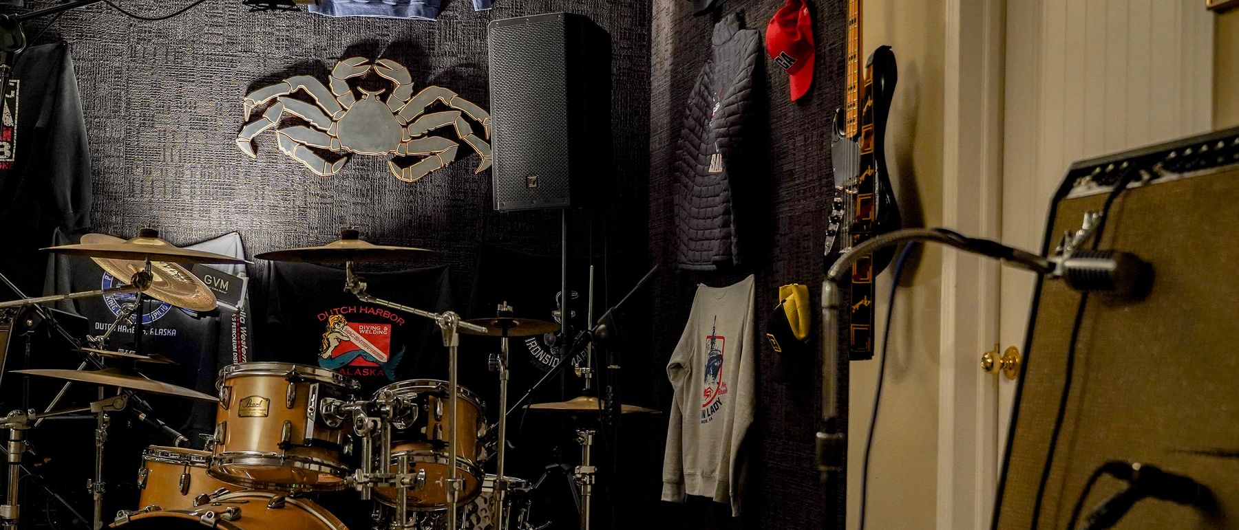 The live room at Studio Hutch: a Pearl drum kit, a miked guitar amp, a bass on the wall, and Bering Sea memorabilia